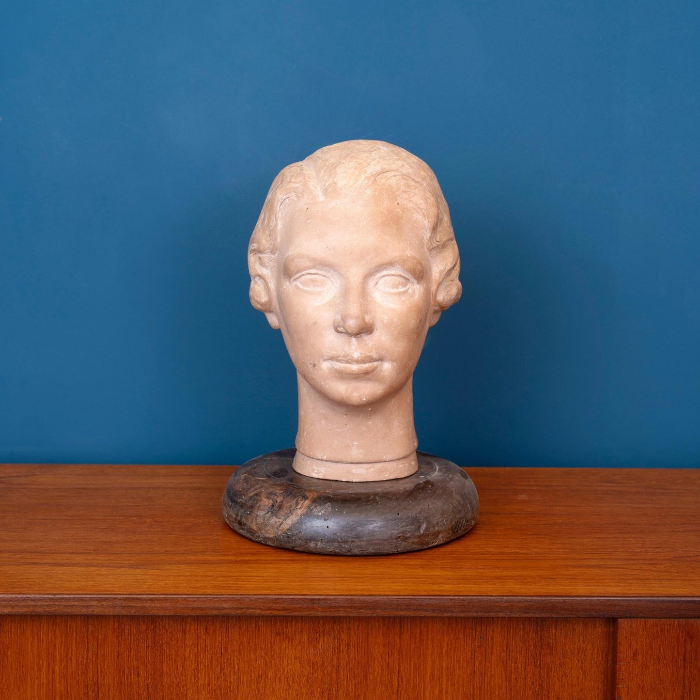Scultura in terracotta raffigurante la testa di una donna, con base in legno e risalente ai primi del ‘900.