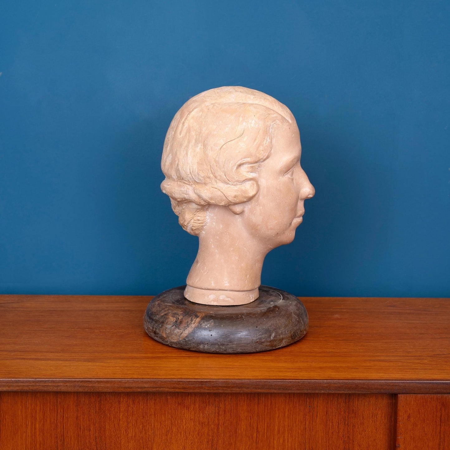Profilo Scultura in terracotta raffigurante la testa di una donna, con base in legno e risalente ai primi del ‘900.