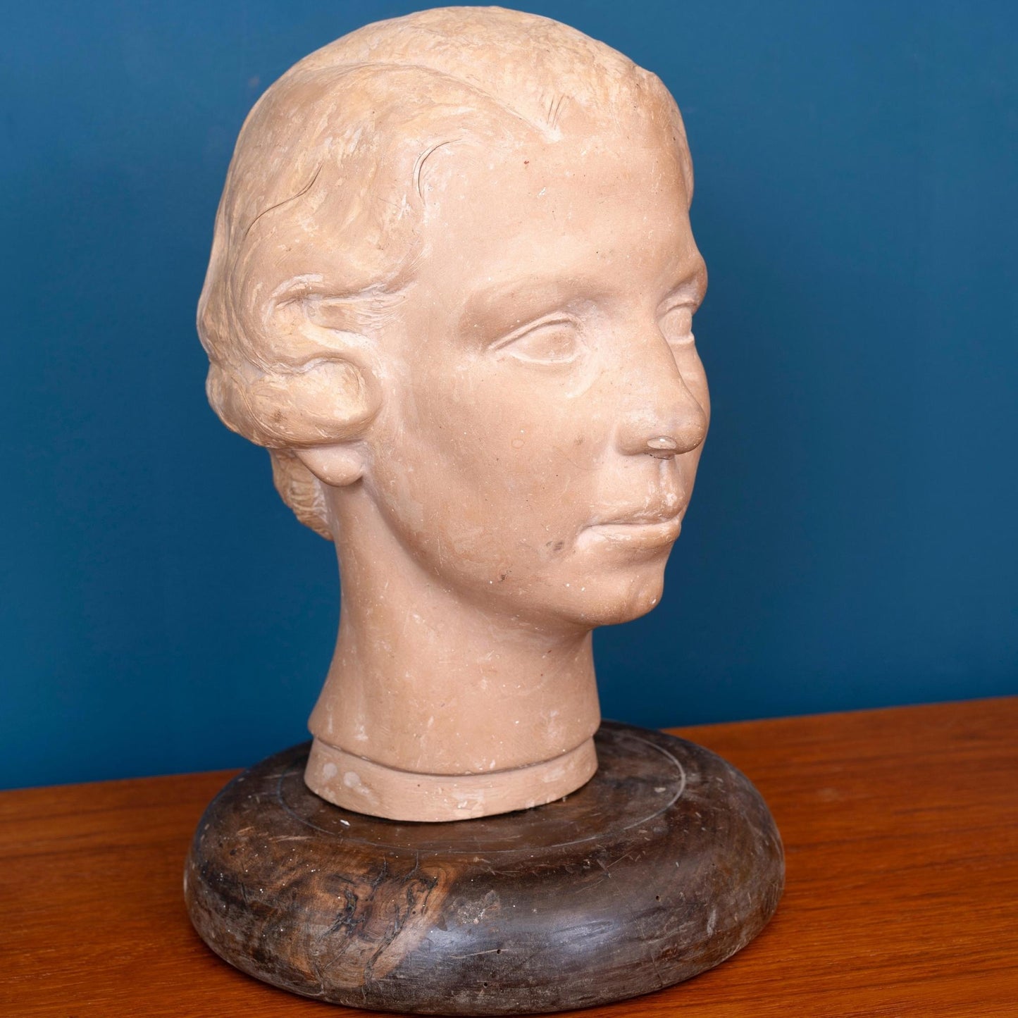 Scultura in terracotta raffigurante la testa di una donna, con base in legno e risalente ai primi del ‘900.