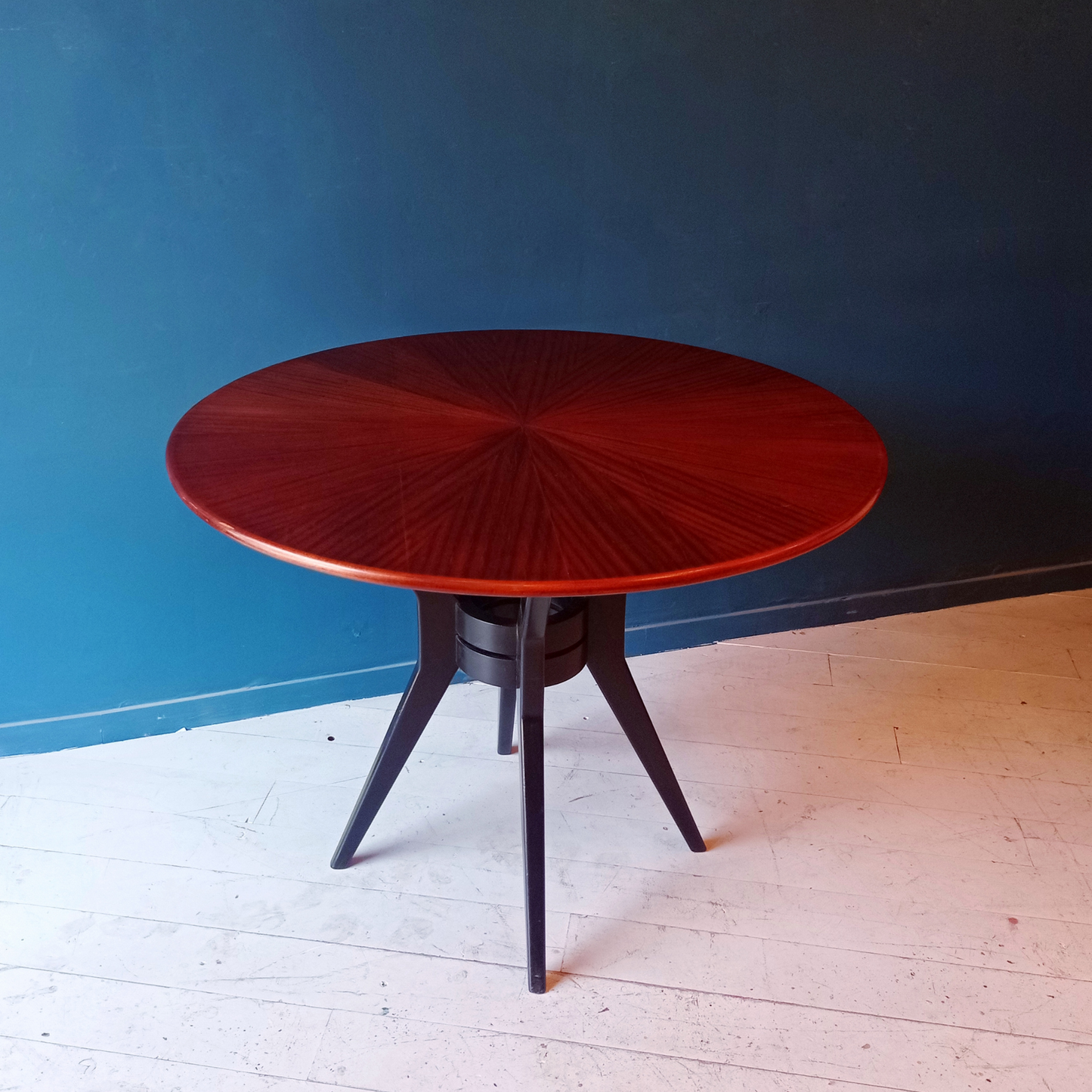 Dettaglio piano tavolo da pranzo tondo vintage in legno rigatino di mogano con gambe ebanizzate, risalente agli anni '50.