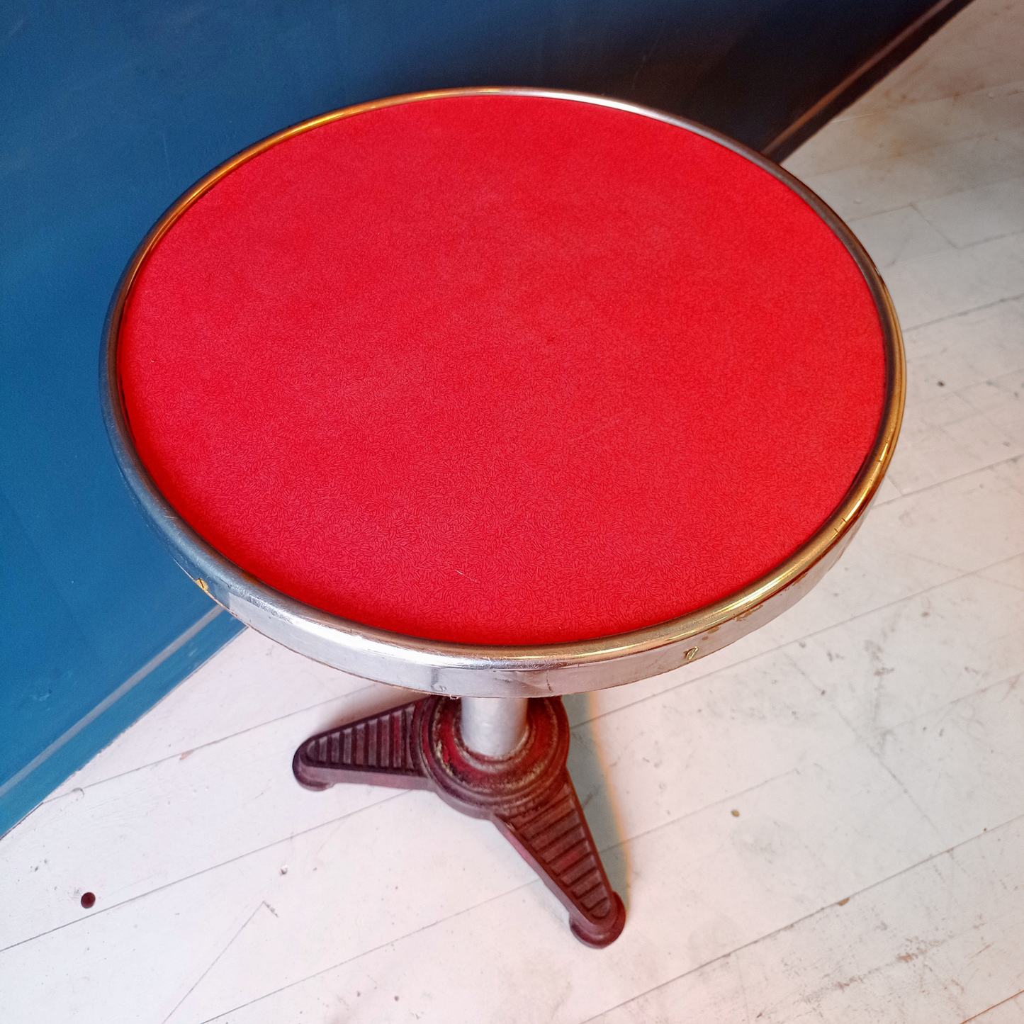 Dettaglio piano tavolino da bistrot francese vintage, risalente agli anni '30. Piano in formica rossa bordata in alluminio, gamba in alluminio e base in ghisa.