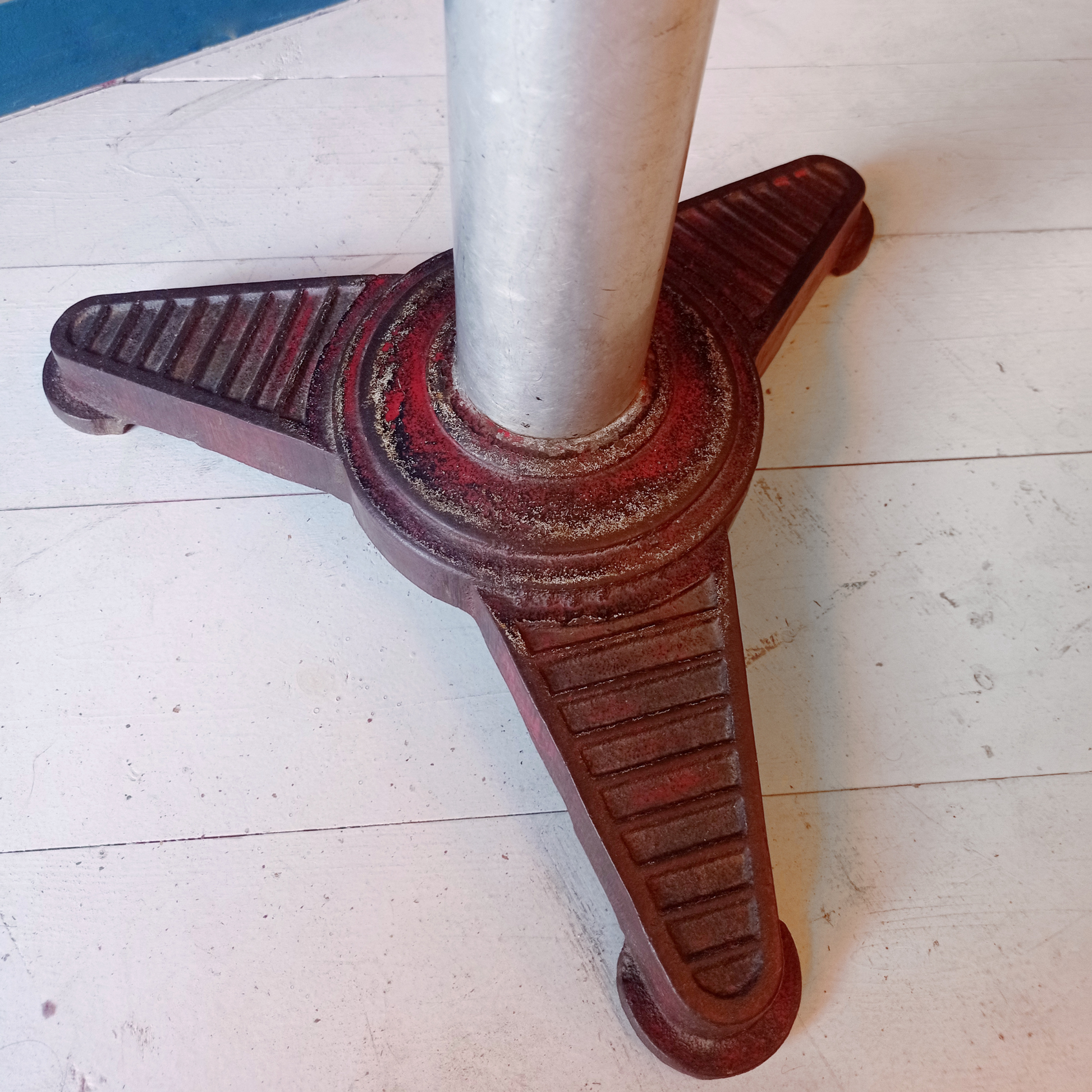 Dettaglio base tavolino da bistrot francese vintage, risalente agli anni '30. Piano in formica rossa bordata in alluminio, gamba in alluminio e base in ghisa.
